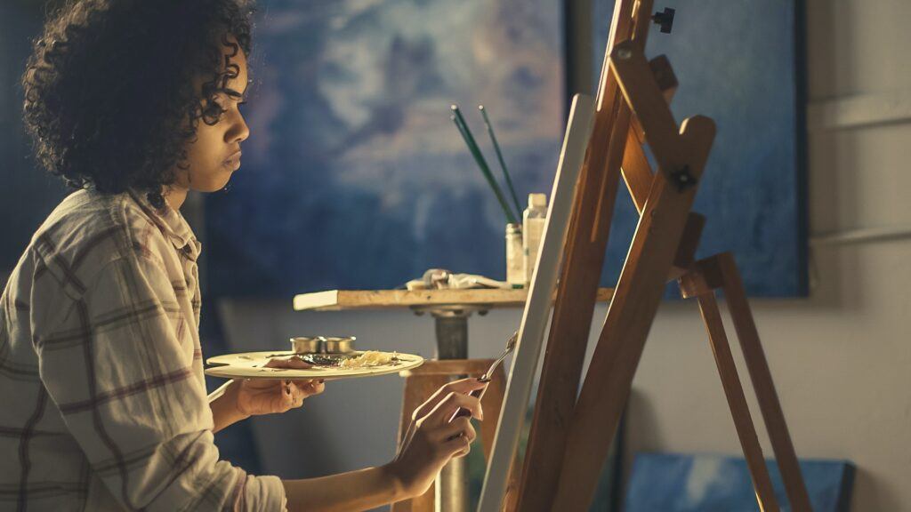 Best ways to make money online as an Artist - Young lady artist hard at work drawing at her easel