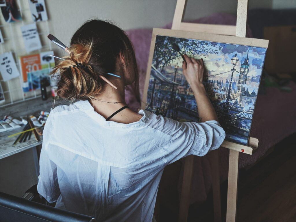 Best ways to make money online as an artist - Young lady artist painting a city scene