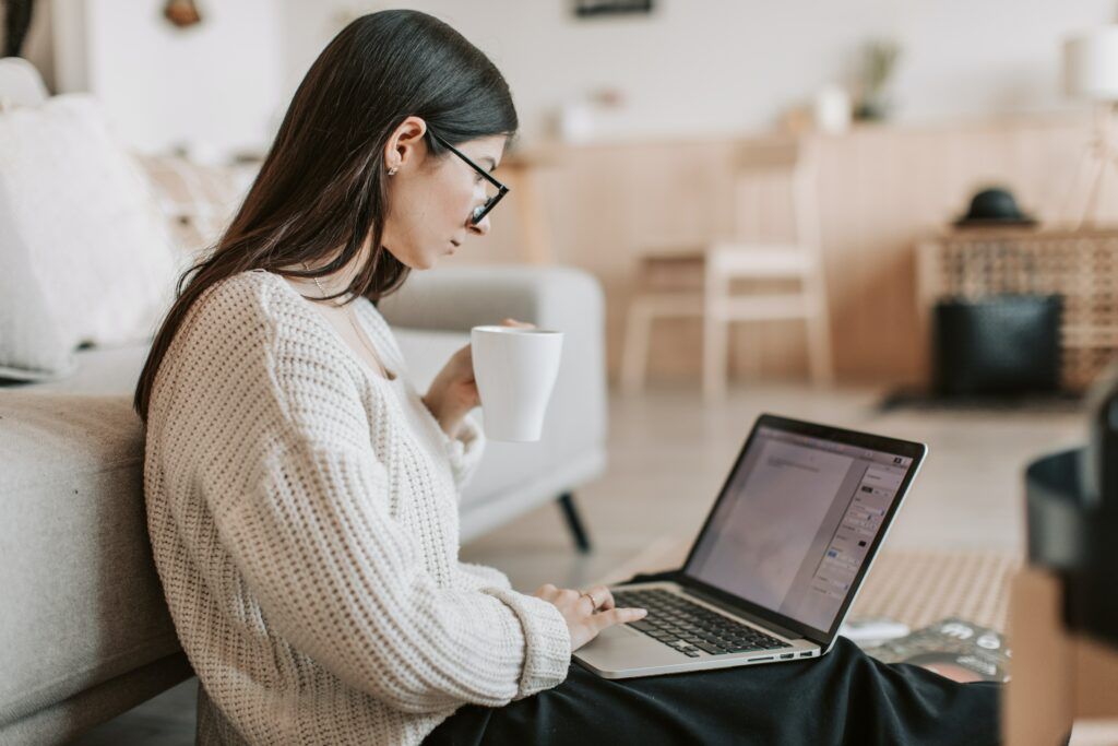 4 steps to $10K per month online - Lady working on her online business from her laptop while enjoying a cup of coffee