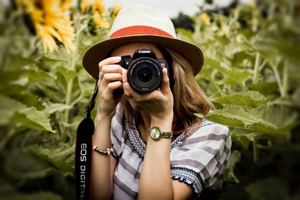 Create your own profitable online photography business - picture of lady photographer looking through her camera at you