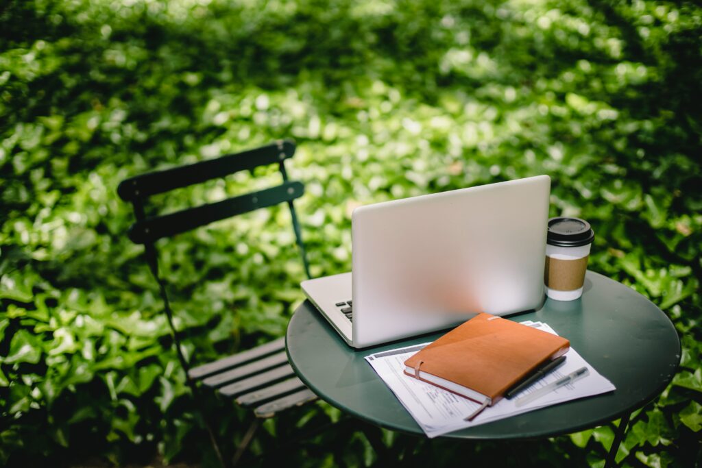 make good money online from gardening - garden blogger with laptop on a small table in the garden