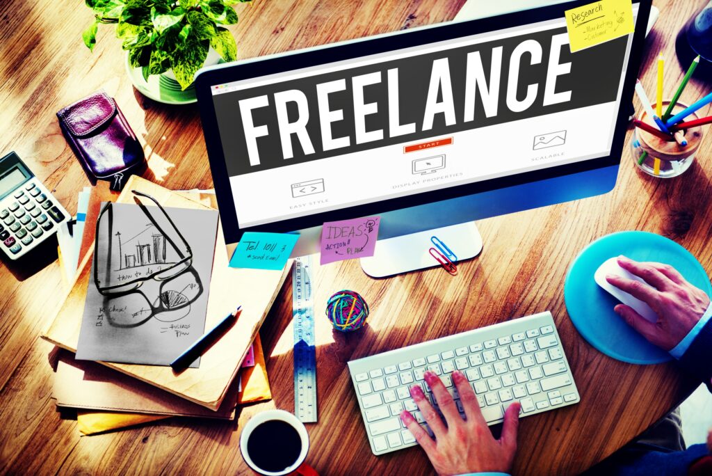Someone working at a computer and across the screen is written the word FREELANCE