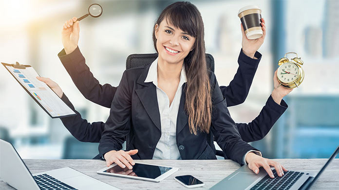 woman working at two computers with 4 extra arms to handle all of the tasks she is trying to complete